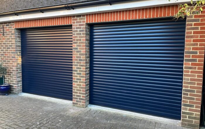 Two blue roller garage doors next to each other, set within a brick wall structure.