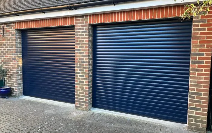 Two blue roller garage doors next to each other, set within a brick wall structure.