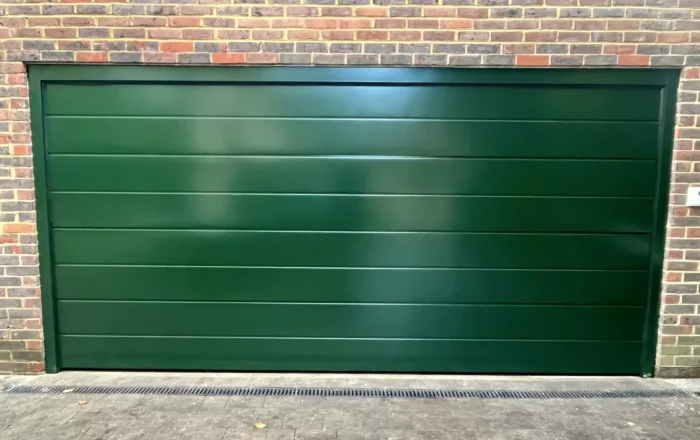 A green, horizontal slatted garage door set against a brick wall.